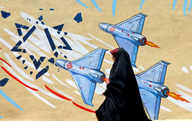 Une Iranienne marche devant une fresque anti-américaine et anti-israélienne, le 8 avril 2026 à Téhéran ( AFP / ATTA KENARE )