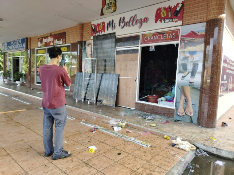 Un homme prend des photos des dégâts dans un magasin après des pillages et de violentes manifestations à Changuinola, au Panama, le 20 juin 2025 ( AFP / DANIEL SANTOS )