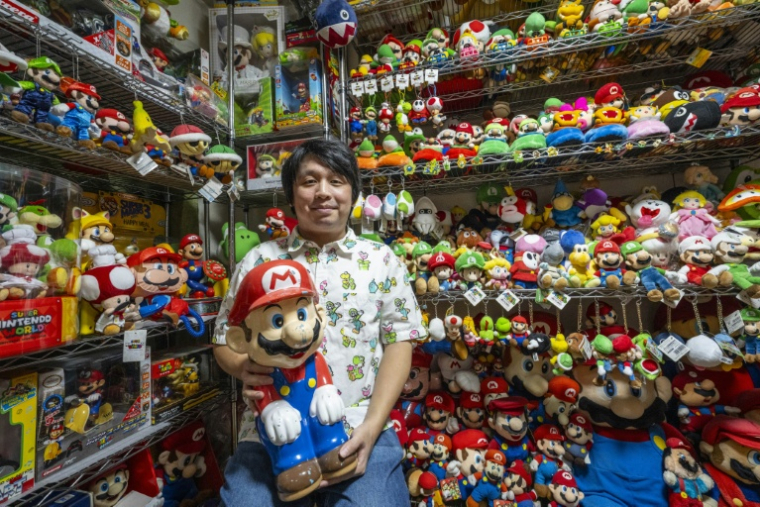 Le collectionneur Kikai pose avec ses pièces de l'univers "Super Mario", chez lui à Mishima, au Japon, le 19 août 2025 ( AFP / Yuichi YAMAZAKI )