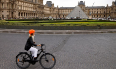Une femme circule en vélo près de la pyramide du musée du Louvre à Paris