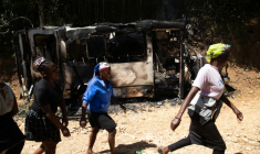 Des habitantes passent devant un véhicule calciné après des violences au cours desquelles plus de vingt personnes ont été tuées par des gangs armés à Kenscoff, près de Port-au-Prince, le 24 août 2026 en Haïti ( AFP / Clarens SIFFROY )