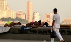 Un homme passe devant des femmes qui dorment sur le Malecon à La Havane lors d'une coupure de courant nationale, le 3 août 2026 ( AFP / YAMIL LAGE )