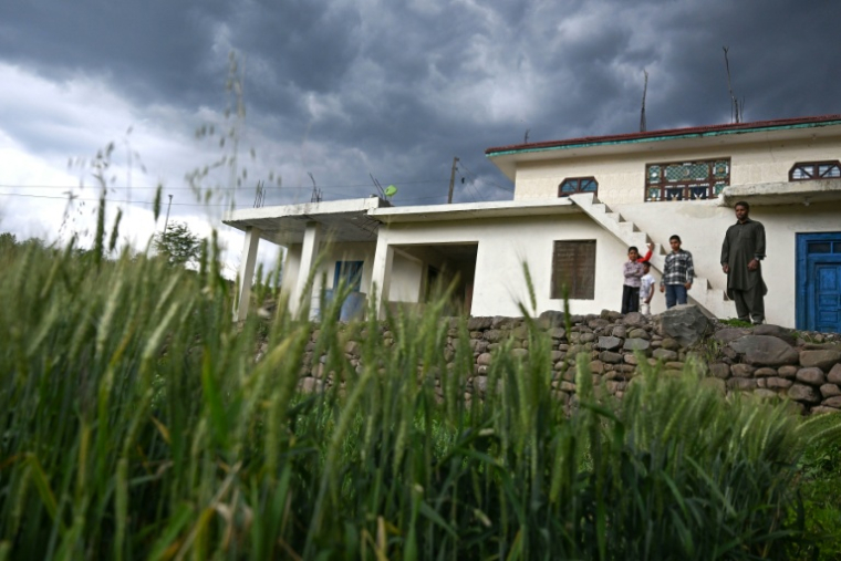 Mohammad Rashid (d) devant sa maison, surmontée d'un bunker récemment construit, dans le village de Kasaliyan, près de la frontière avec le Pakistan, le 6 avril 2026 en Inde ( AFP / Tauseef MUSTAFA )