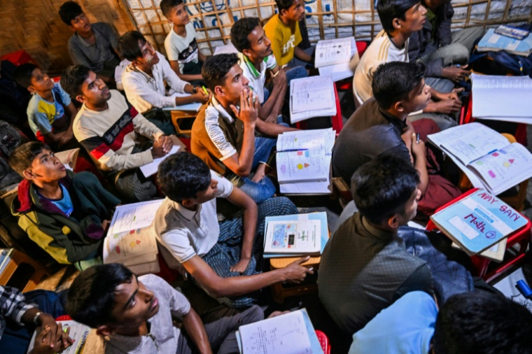 Des réfugiés rohingyas dans une salle de classe bondée d'un centre éducatif de fortune au camp de réfugiés de Kutupalong, le 17 décembre 2025  à Ukhia, au Bangladesh ( AFP / Munir UZ ZAMAN )
