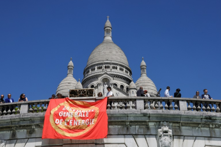 Des membres d'Extinction Rebellion (XR) et des militants pour le climat arborent une banderole "Assemblée générale de l'énergie" lors d'une manifestation avant l'assemblée générale ordinaire et extraordinaire des actionnaires de TotalEnergies, à la Basilique du Sacré-Cœur de Montmartre, à Paris, le 23 mai 2025 ( AFP / GEOFFROY VAN DER HASSELT )