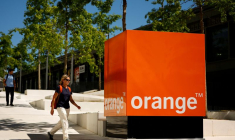 Une femme passe devant le logo d'Orange au siège de la société à Issy-les-Moulineaux