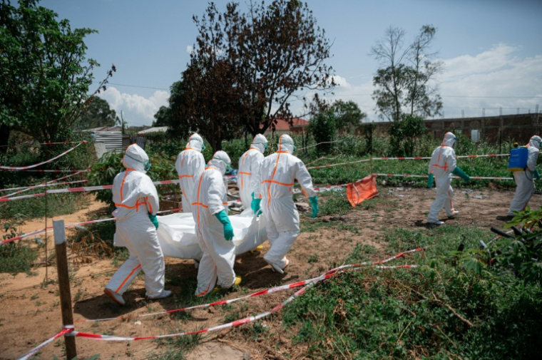 Des bénévoles de la Croix-Rouge, en combinaison de protection, transportent le corps d'une victime de la maladie à virus Ebola au centre de santé de Rwampara, le 8 juin 2026 en RDC ( AFP / Jospin Mwisha )