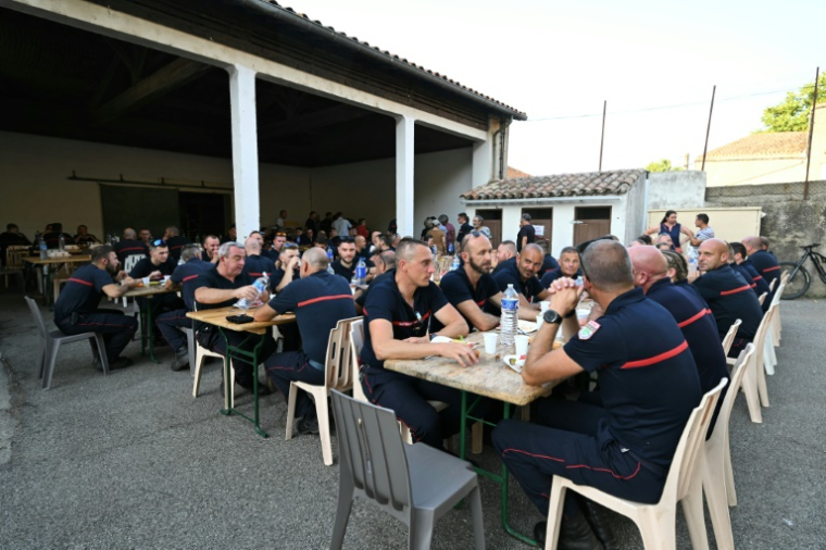 Les sapeurs-pompiers venus en renfort dans l'Aude lors d'un repas organisé en leur honneur à Talairan, dans l'Aude, le 8 août 2025 ( AFP / Bertrand GUAY )