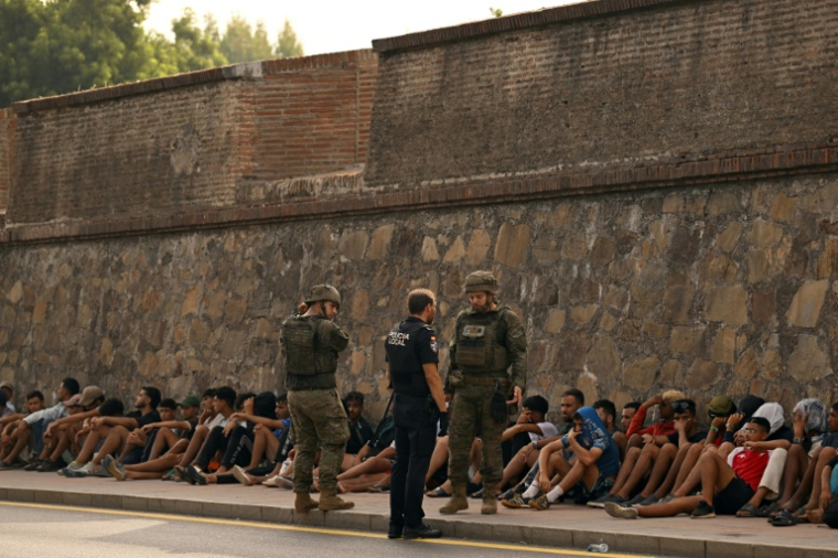 Des militaires espagnols et un policier devant des migrants qui étaient entrés illégalement dans l'enclave espagnole de Ceuta et qui sont peu à peu renvoyés au Maroc, le 1er août 2026 à Ceuta  ( AFP / JORGE GUERRERO )