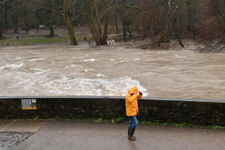 Un passant sur les berges de l'Hérault, qui a débordé suite aux fortes pluies à Laroque, le 22 décembre 2025 ( AFP / Sylvain THOMAS )