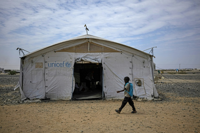 Un élève passe devant une tente servant d'école dans un camp de personnes déplacées par la guerre, près de Port-Soudan, le 26 avril 2026 au Soudan ( AFP / Khaled DESOUKI )