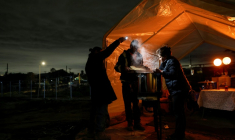 Un couple qui a perdu sa maison dans l'immense incendie de janvier 2025 cuisine une spécialité mexicaine sous une tente d'abri temporaire pour Noël, le 23 décembre 2025 à Altadena, à l'approche de la "rivière atmosphérique" qui doit traverser le sud de l'Etat cette semaine ( GETTY IMAGES NORTH AMERICA / MARIO TAMA )