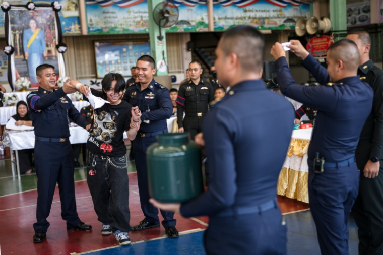 Un jeune homme sourit (2e à gauche) après avoir tiré une carte lui permettant d'être exempté de service militaire le 7 avril 2026, à Bangkok, en Thaïlande ( AFP / chanakarn LAOSARAKHAM )