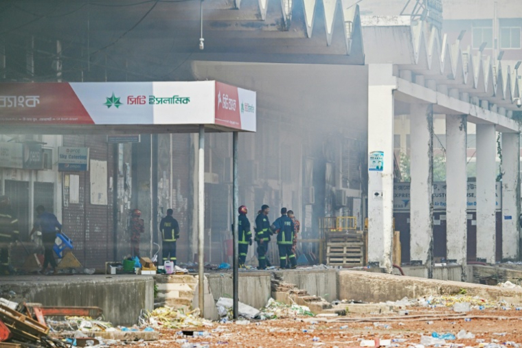 Des pompiers inspectent le terminal de fret de l'aéroport international Hazrat Shahjalal de Dacca au Bangladesh, le 19 octobre 2025, au lendemain de l'incendie qui l'a ravagé ( AFP / Munir UZ ZAMAN )