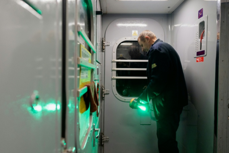 Le contrôleur Mykola Kryvenko, près de la porte, une lampe de poche à la main, alors que les passagers sont évacués du train en raison de la menace d’un drone russe, lors du trajet Kharkiv-Kiev, le 21 octobre 2026 en Ukraine ( AFP / Tetiana DZHAFAROVA )