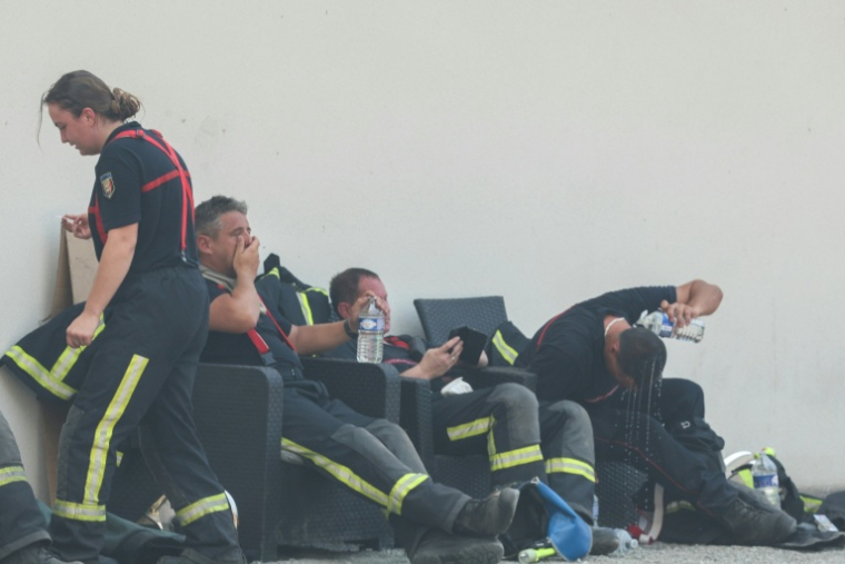 Des pompiers se reposent avec des bouteilles d'eau pendant une pause au cours des opérations de lutte contre un incendie de forêt près de Lanton, dans le sud-ouest de la France, le 29 juillet 2026 ( AFP / Alain JOCARD )