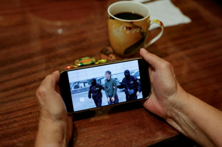 Une personne regarde sur un smartphone un fil d'actualité diffusant des images du FSB russe montrant l'opération d'interpellation d'un journaliste japonais accusé d'espionnage, à Moscou, le 13 octobre 2026 ( AFP / Tatyana MAKEYEVA )