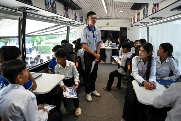 Dans un bus transformé en musée sur roues, des élèves cambodgiens se familiarisent avec l'histoire du génocide des Khmers rouges, dans le district de Phnom Srok, dans la province de Banteay Meanchey, le 24 mars 2025 ( AFP / TANG CHHIN Sothy )