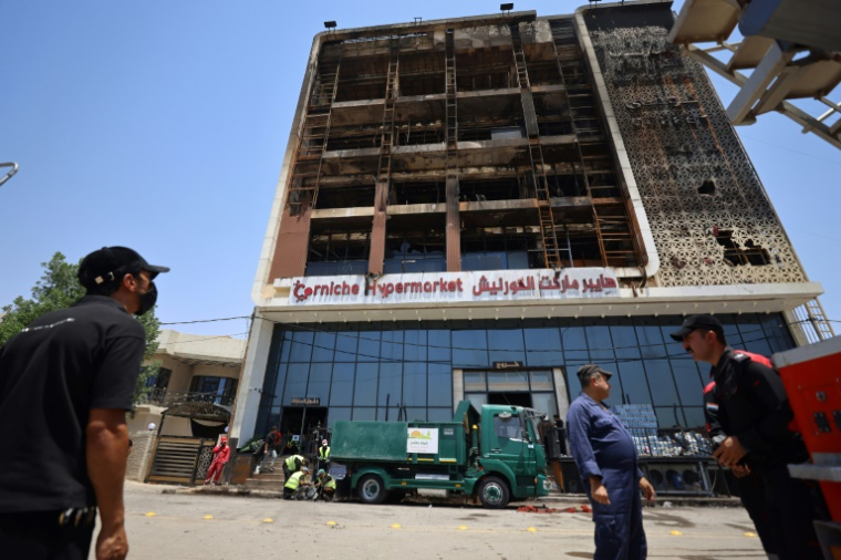 Opération de nettoyage devant le bâtiment du centre commercial Hyper Mall ravagé par un incendie dans la nuit tuant plus de 60 personnes, le 17 juillet 2025 à Kut, dans l'est de l'Irak ( AFP / AHMAD AL-RUBAYE )