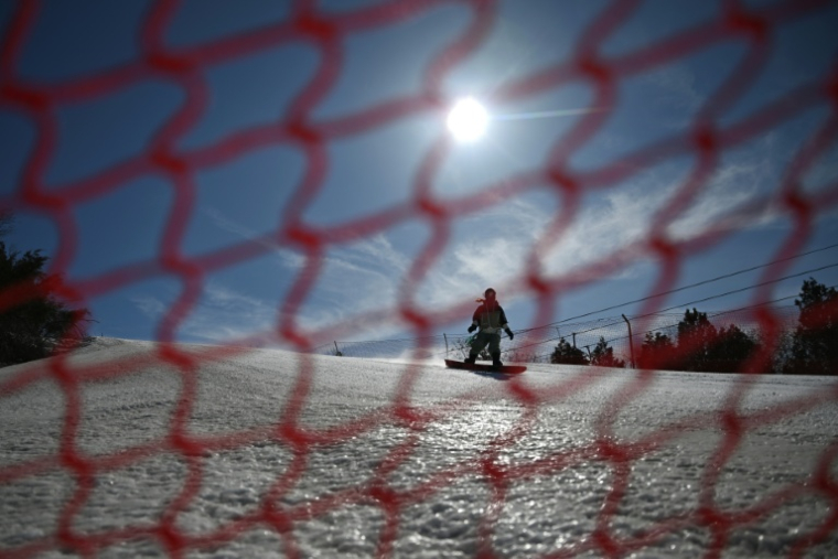 Un touriste fait du snowboard sur les pistes de la station de ski de Lianhuashan, en périphérie de Pékin, le 16 février 2026 en Chine ( AFP / Pedro PARDO )