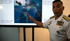 Le porte-parole de la marine philippine Roy Vincent Trinidad, montre une photo de la saisie de bouteilles appartenant à des pêcheurs chinois, soupçonnées de contenir du cyanure, dans les eaux du banc Second Thomas, en mer de Chine méridionale, lors d'une conférence de presse à Manille, le 13 avril 2026 ( AFP / Ted ALJIBE )