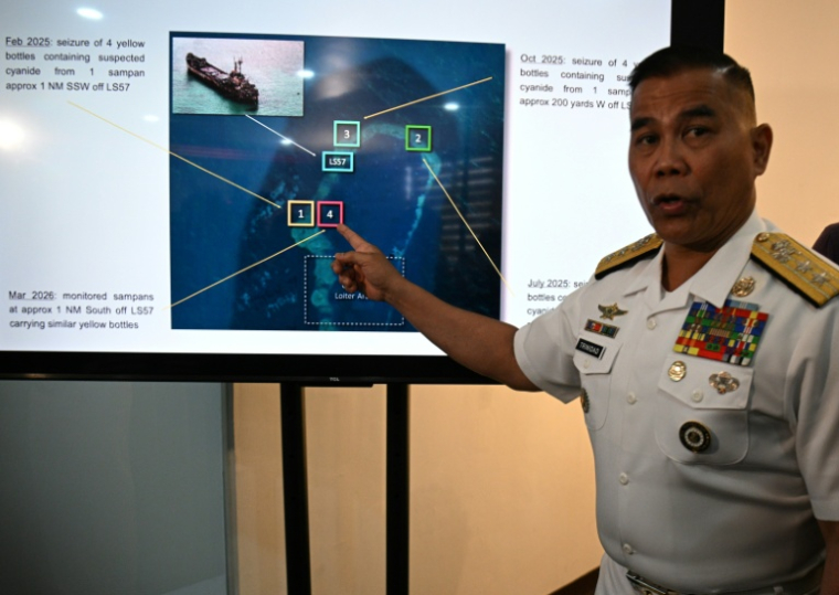 Le porte-parole de la marine philippine Roy Vincent Trinidad, montre une photo de la saisie de bouteilles appartenant à des pêcheurs chinois, soupçonnées de contenir du cyanure, dans les eaux du banc Second Thomas, en mer de Chine méridionale, lors d'une conférence de presse à Manille, le 13 avril 2026 ( AFP / Ted ALJIBE )