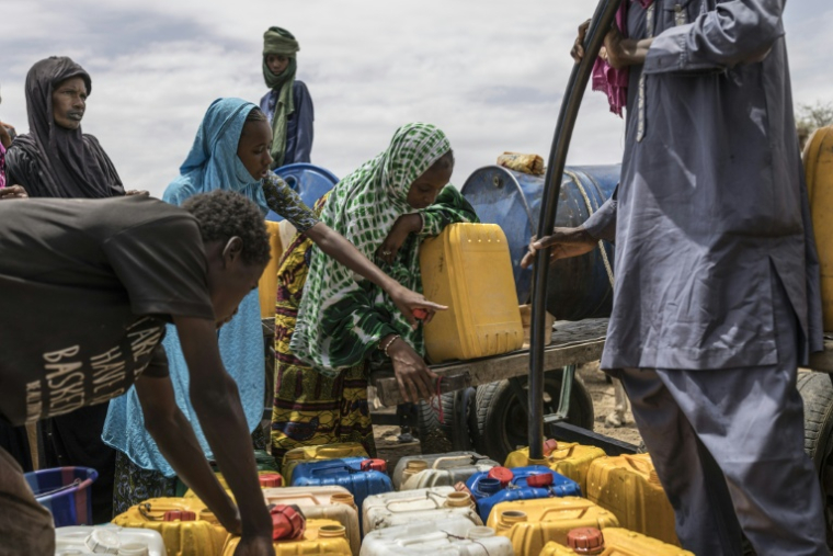 Un enfant montre du doigt un bidon près d'un point d'eau dans un campement de fortune à Douéinkara, en Mauritanie, près de la frontière avec le Mali, le 29 avril 2026 ( AFP / PATRICK MEINHARDT )