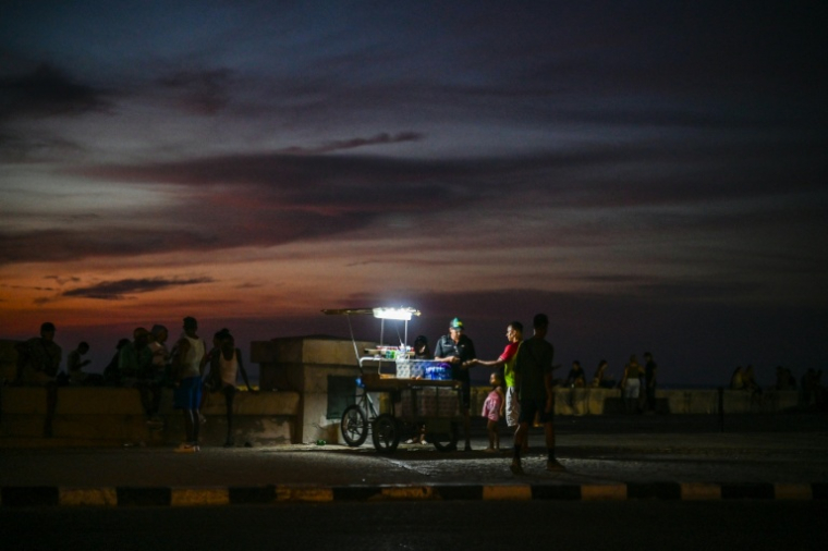 Un vendeur de rue utilise une lampe portative sur le Malecón, le 6 juillet 2026 à La Havane, lors d'une panne d'électricité nationale à Cuba ( AFP / ADALBERTO ROQUE )