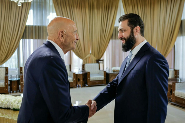 Photo fournie par la présidence syrienne montrant une poignée de mains entre l'émissaire américain Tom Barrack et le président Ahmad al-Chareh, le 18 janvier 2026 à Damas. ( Syrian Presidency Telegram Page / Handout )