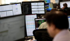Les traders consultent des informations financières sur des écrans d'ordinateur dans la salle des marchés d'IG Index