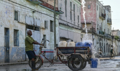 Un homme remplit des récipients d'eau à un point de ravitaillement public dans une rue de La Havane, le 5 octobre 2026 ( AFP / YAMIL LAGE )