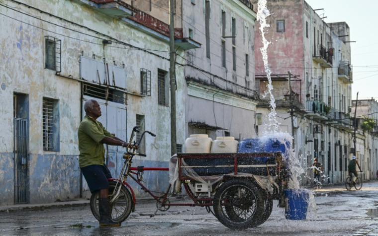 Un homme remplit des récipients d'eau à un point de ravitaillement public dans une rue de La Havane, le 5 octobre 2026 ( AFP / YAMIL LAGE )