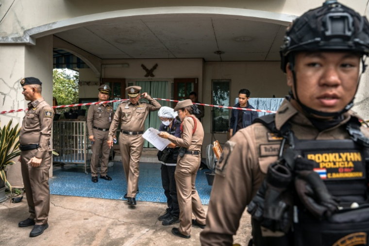 Des policiers en faction devant la maison des grands-parents de l'adolescent tueur, dans la province de Nonthaburi au nord de la capitale thaïlandaise Bangkok, le 7 août 2026  ( AFP / Chanakarn LAOSARAKHAM )