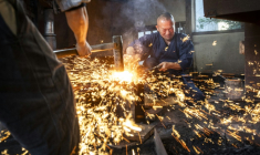 Le forgeron Akihira Kawasaki (d) maintient l'acier sur une enclume tandis que son apprenti Toru Watanabe martèle le métal pour forger des lames de katana, le 9 janvier 2026 à Misato, au Japon ( AFP / Yuichi YAMAZAKI )