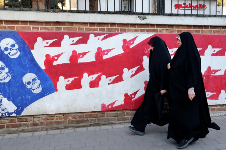 Des Iraniennes passent devant une fresque peinte sur les murs extérieurs de l'ancienne ambassade américaine à Téhéran, le 1er février 2026 ( AFP / ATTA KENARE )
