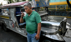 Le chauffeur de jeepney Eric Helera boit un café pendant une pause avant de prendre la route à Manille, le 23 mars 2026 ( AFP / Ted ALJIBE )