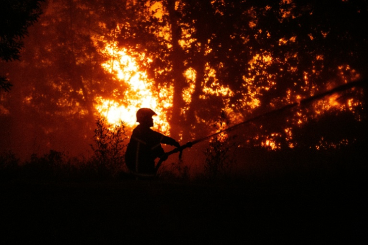 Un sapeur-pompier arrose la forêt près d'une zone résidentielle menacée par l'incendie proche de Lège-Cap-Ferret en Gironde, le 23 juillet 2026 ( AFP / JULIEN DE ROSA )