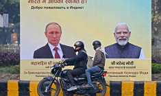 Un motard passe devant des portraits du président russe Vladimir Poutine, à gauche, et du Premier ministre indien Narendra Modi, à droite, à New Delhi le 4 décembre 2025 ( AFP / Sajjad HUSSAIN )