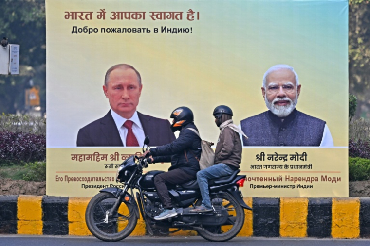 Un motard passe devant des portraits du président russe Vladimir Poutine, à gauche, et du Premier ministre indien Narendra Modi, à droite, à New Delhi le 4 décembre 2025 ( AFP / Sajjad HUSSAIN )