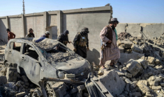 Des membres de la sécurité talibane marchent à côté d'une voiture endommagée, le 16 octobre 2025 dans le district de Spin Boldak ( AFP / Sanaullah SEIAM )