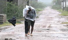 Des habitants se protègent de la pluie et du vent à Kakinada en Inde le 27 octobre 2026 avant l'arrivée du cyclone Arnab ( AFP / Noah SEELAM )