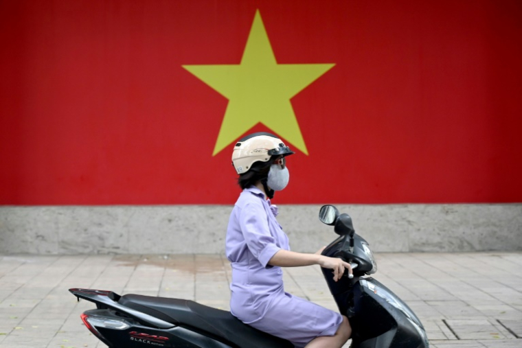 Une femme conduit un scooter à Hanoi, le 17 juillet 2025  ( AFP / Nhac NGUYEN )