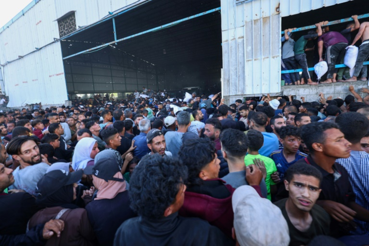 Des Palestiniens déplacés se ruent sur un entrepôt du Programme alimentaire mondial à Deir el-Balah, dans le centre de la bande de Gaza, le 28 mai 2025 ( AFP / Eyad BABA )