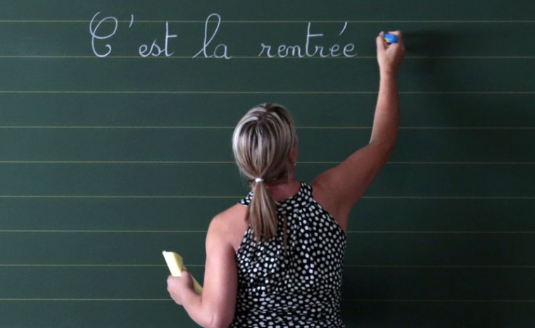 Une enseignante écrit une phrase au tableau de sa classe le premier jour de la rentrée scolaire dans une école primaire de Nice