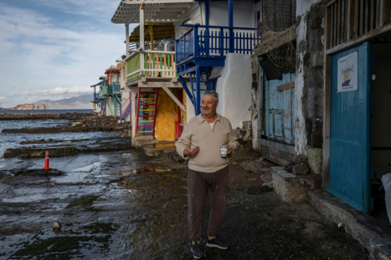 Un habitant devant des chambres à louer dans le village de Klima, sur l'île grecque de Milos, en mer Égée, le 4 février 2026 ( AFP / Aris MESSINIS )