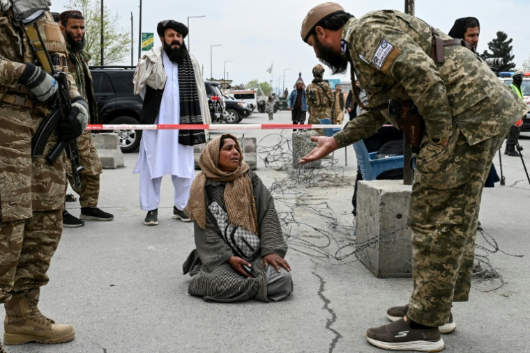Un membre des forces de sécurité talibanes et Samira Muhammadi, lors de la deuxième cérémonie d’obsèques collectives à la mosquée Eid Gah à Kaboul, le 26 mars 2026 ( AFP / Wakil KOHSAR )
