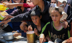 Des enfants palestiniens font la queue pour obtenir un repas chaud lors d'une distribution assurée par une cuisine soldiaire au camp de réfugiés de Nousseriat, dans le centre de la bande de Gaza, le 5 mai 2025 ( AFP / Eyad BABA )
