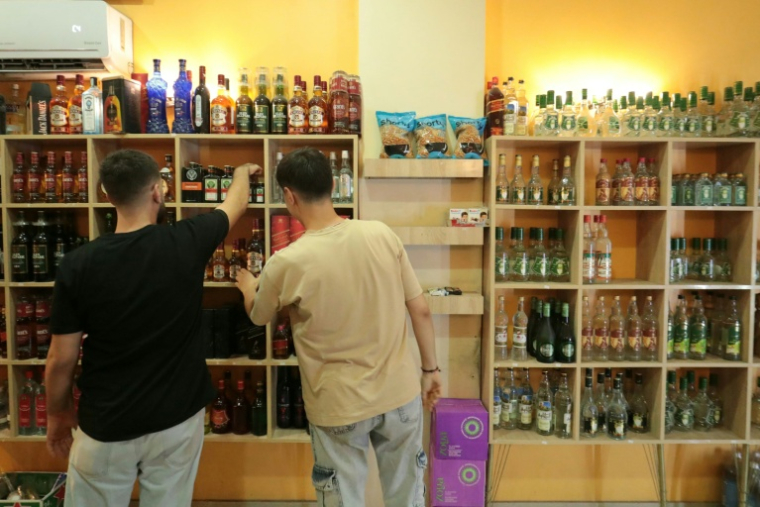 Des clients regardent des bouteilles d'alcool en vente dans un magasin de Qamichli, ville kurde du nord-est de la Syrie, le 18 août 2026 ( AFP / Delil SOULEIMAN )