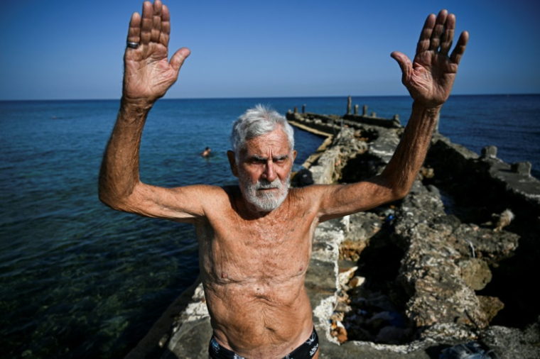 Orestes Quintana, 87 ans, membre du club "Jeunesse accumulée", s'échauffe avant de nager dans une piscine d'eau de mer à La Havane, le 17 mai 2025 ( AFP / YAMIL LAGE )