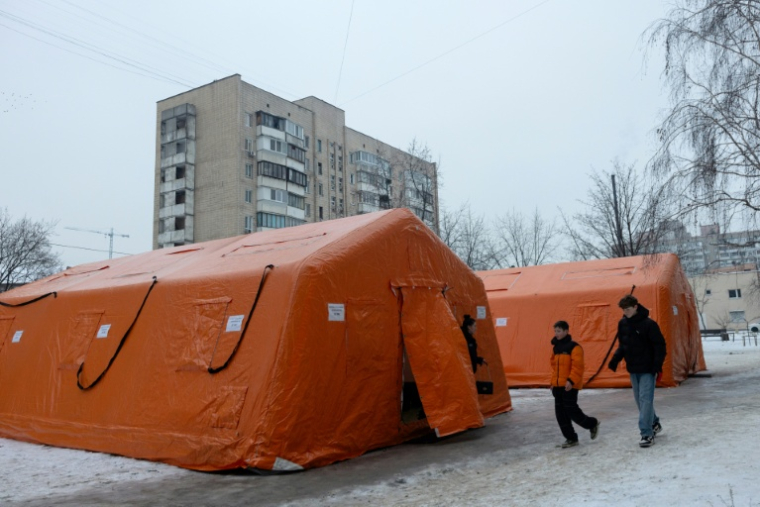 Des adolescents passent devant des tentes installées à Kiev pour permettre aux habitants privés de courant et de chauffage de se réchauffer et de charger leurs appareils, le 11 janvier 2026  ( AFP / Tetiana DZHAFAROVA )